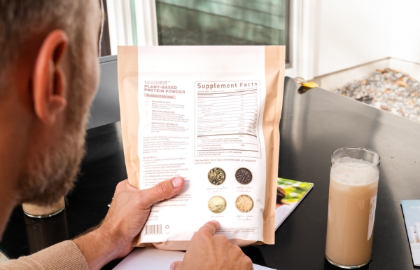 A man reading the back of the bag for the Plant-Based Protein Powder.